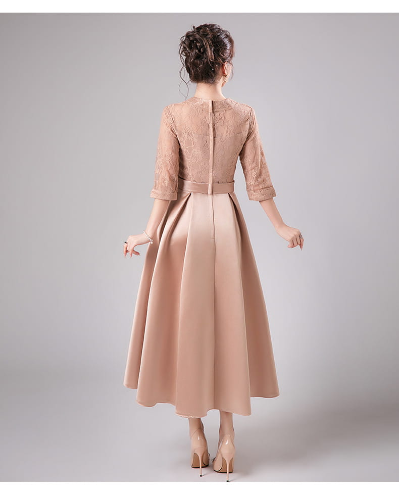 Robe midi d’anniversaire en dentelle et satin beige, avec des manches trois-quarts et une taille ajustée.