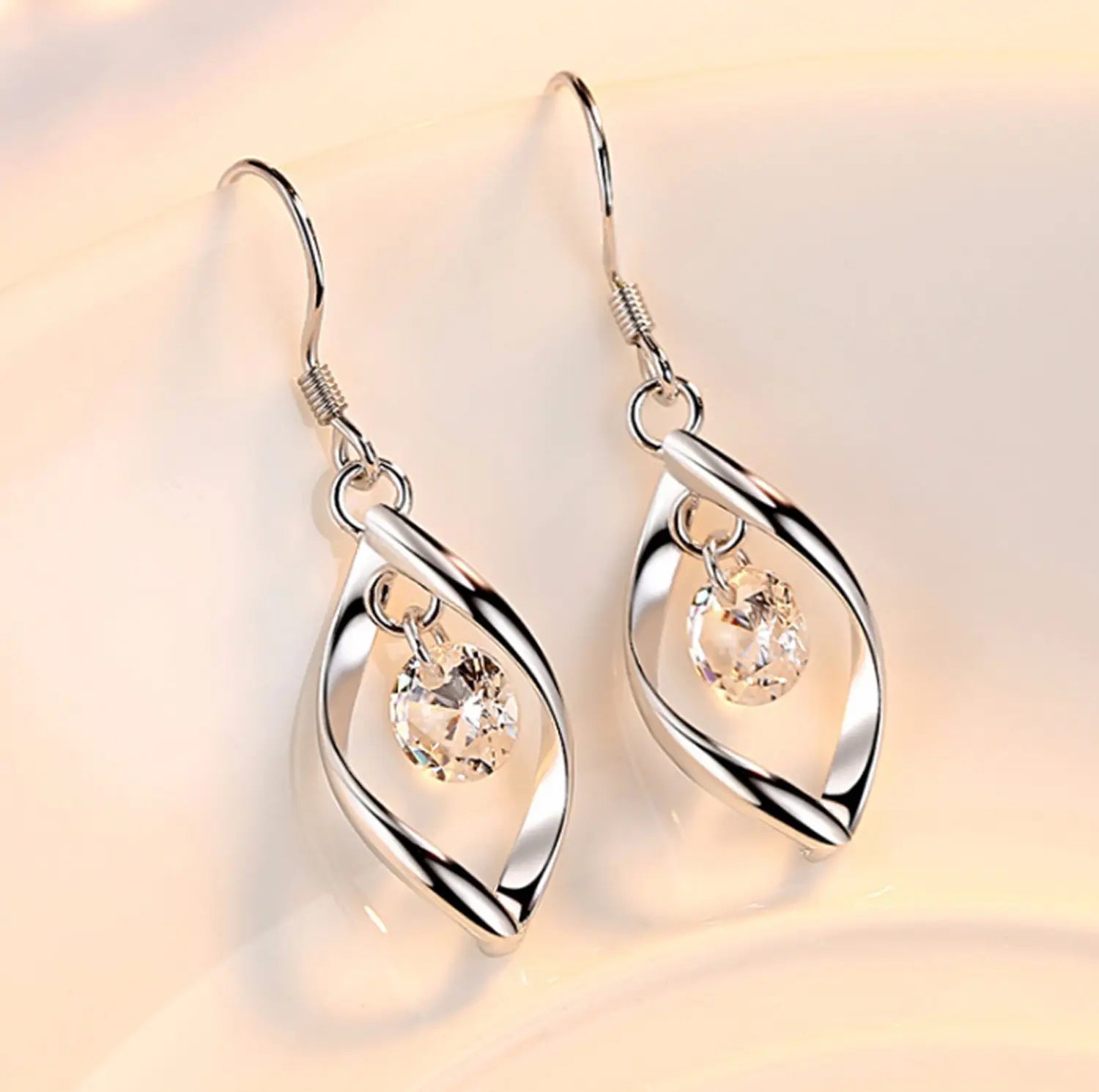 Twisted teardrop silver earrings feature a twisted design with faceted clear crystal accents.
