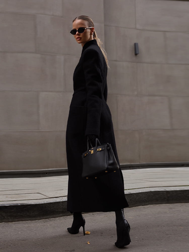 black leather handbag with gold-tone hardware complementing a charcoal gray wool coat women waisted long outerwear.