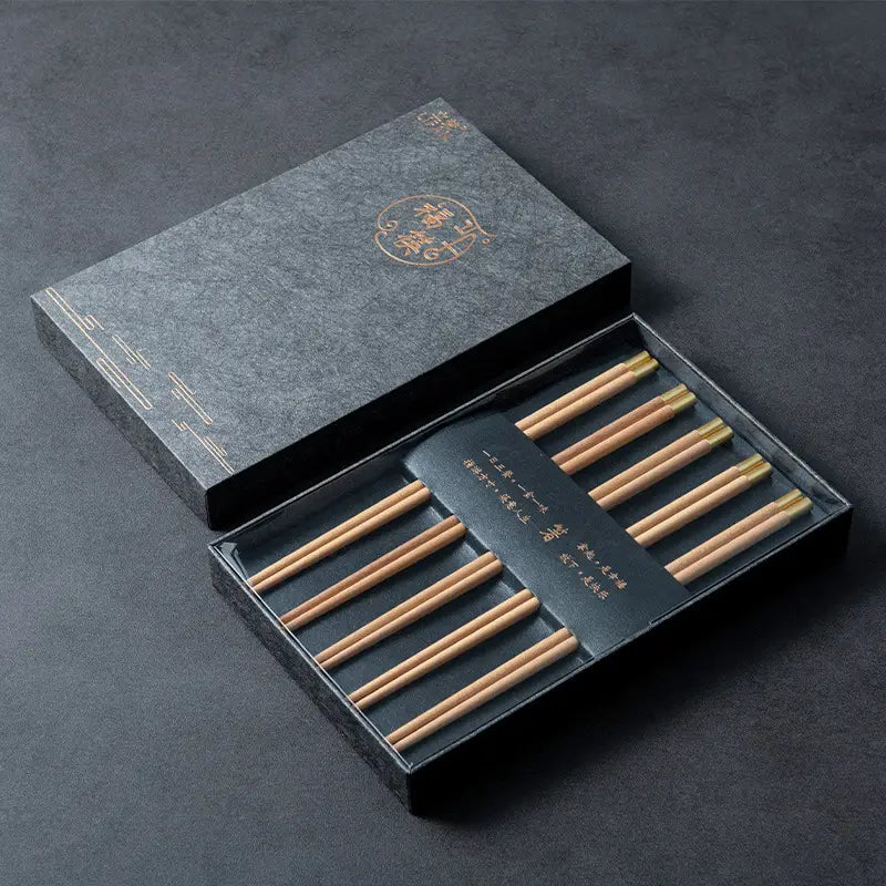 Set aus fünf Paar eleganten hölzernen Essstäbchen mit goldfarbenen Spitzen in einer anspruchsvollen dunkelgrauen Geschenkbox.