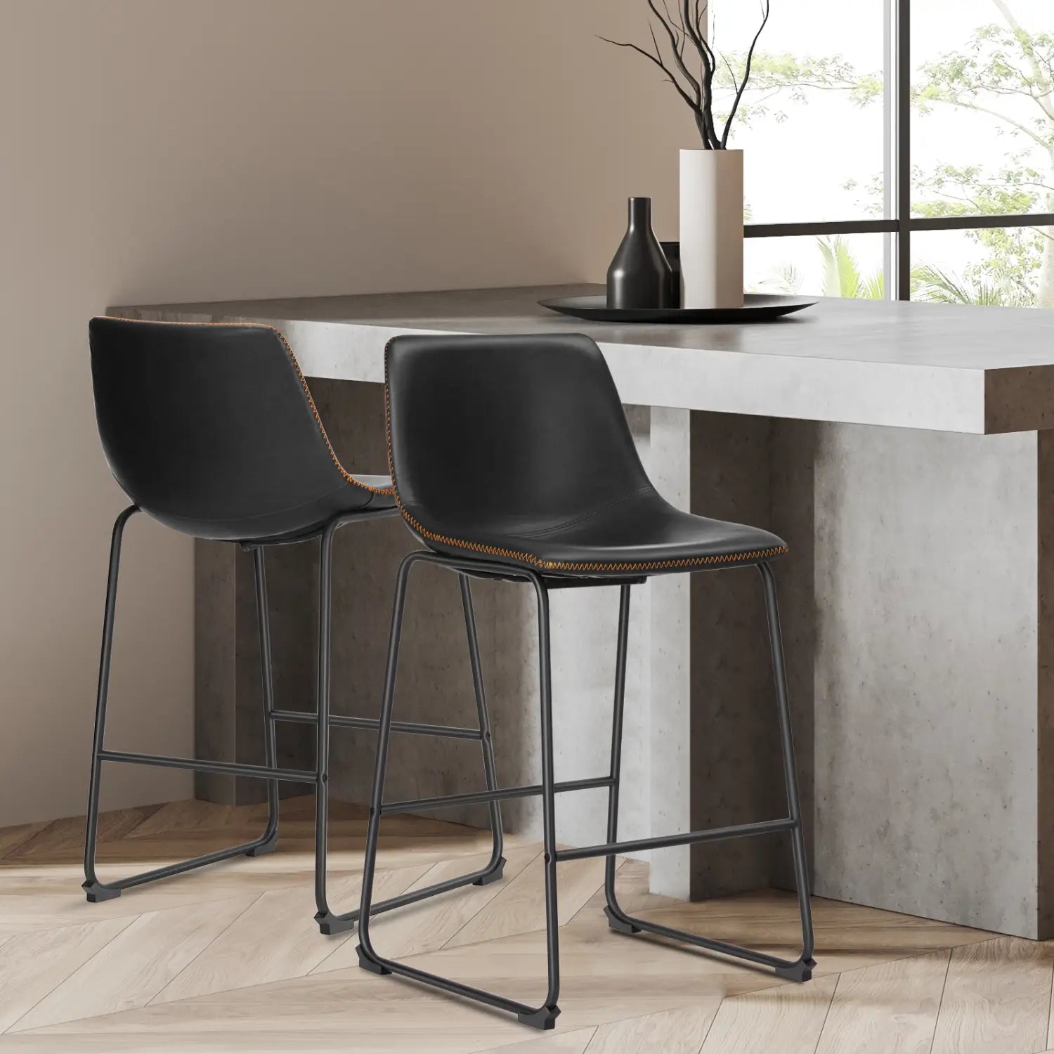 Ensemble de deux chaises de comptoir de style milieu du siècle, comprenant des tabourets de bar en cuir noir avec cadres métalliques et une couture beige contrastante.