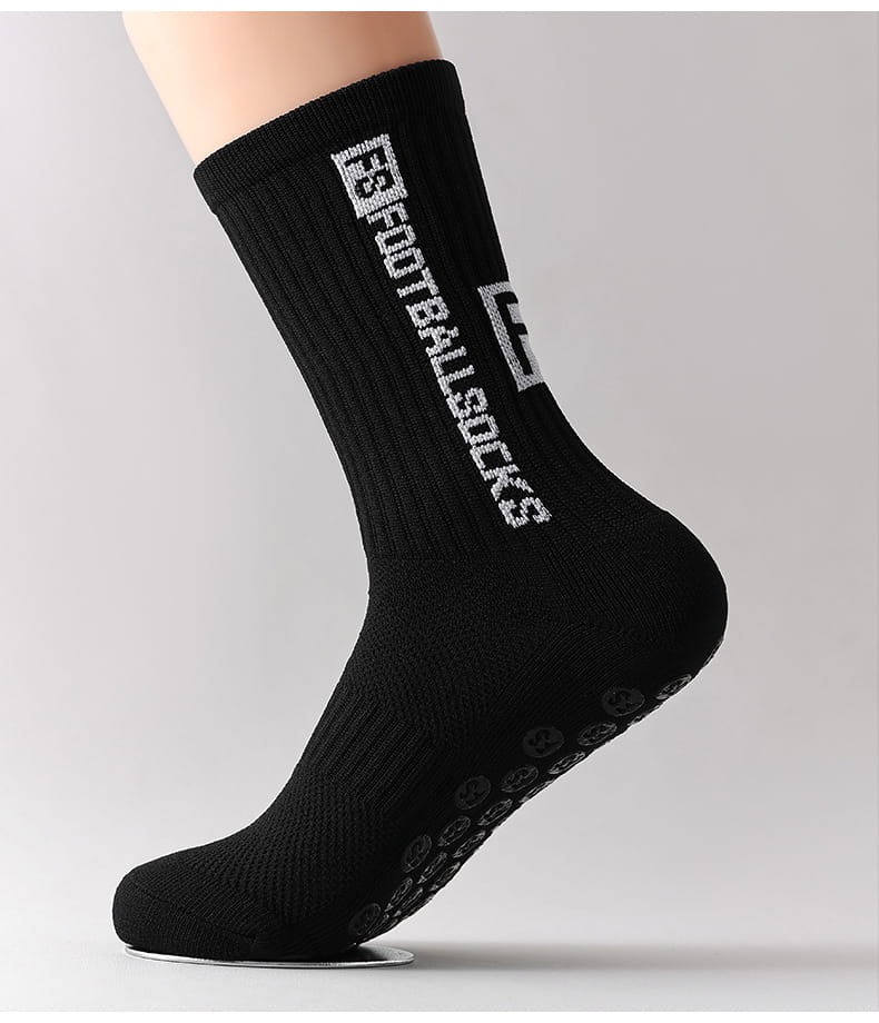 black athletic anti-slip football grip sock for men with white football socks text and logo on the back side featuring a textured grip pattern on the sole