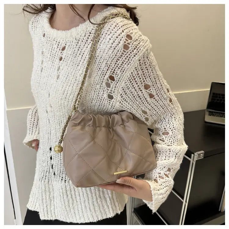 beige quilted faux leather crossbody bag with drawstring closure gold-tone chain strap and decorative ball charm