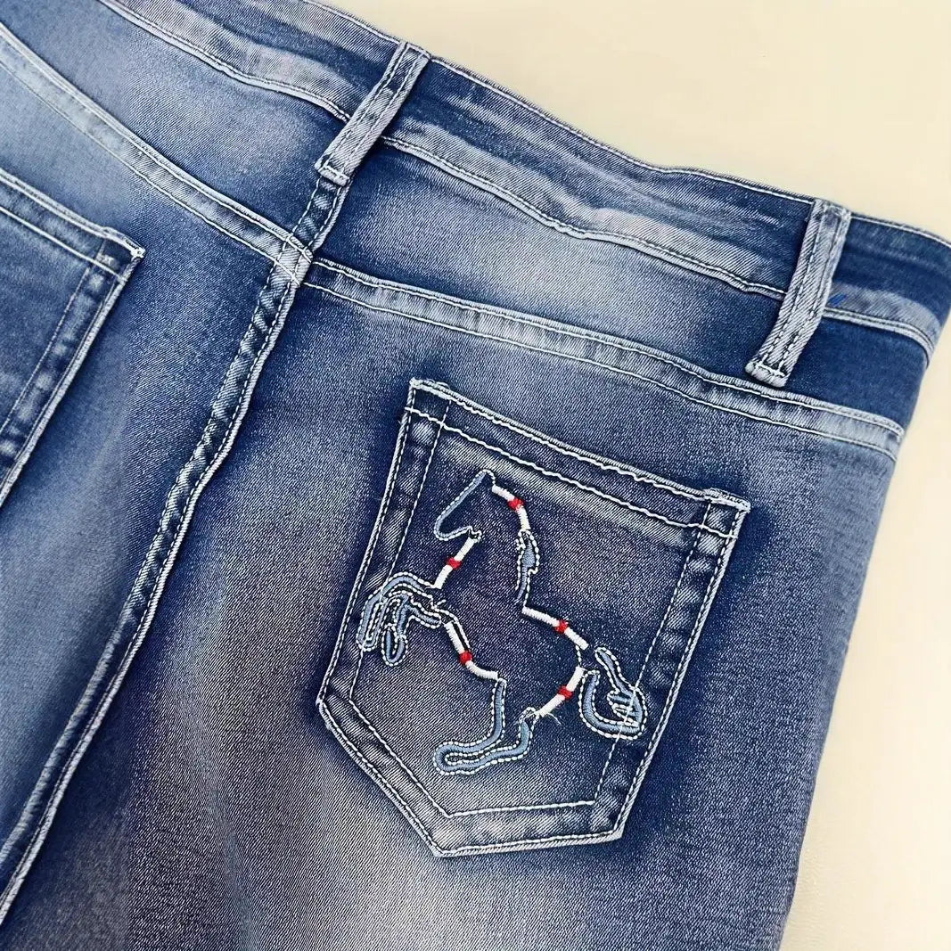 L’image montre la face arrière des jeans droits en denim bleu, avec une poche arrière brodée d’un contour de cheval blanc, rehaussé par des surpiqûres rouges.