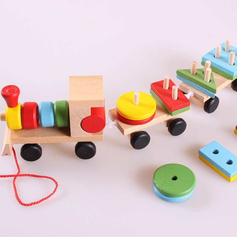 Jouet éducatif en bois de type train pour empiler, présentant des blocs circulaires et géométriques colorés sur ses wagons, avec une corde rouge pour tirer, conçue comme un trieur de formes éducatif.