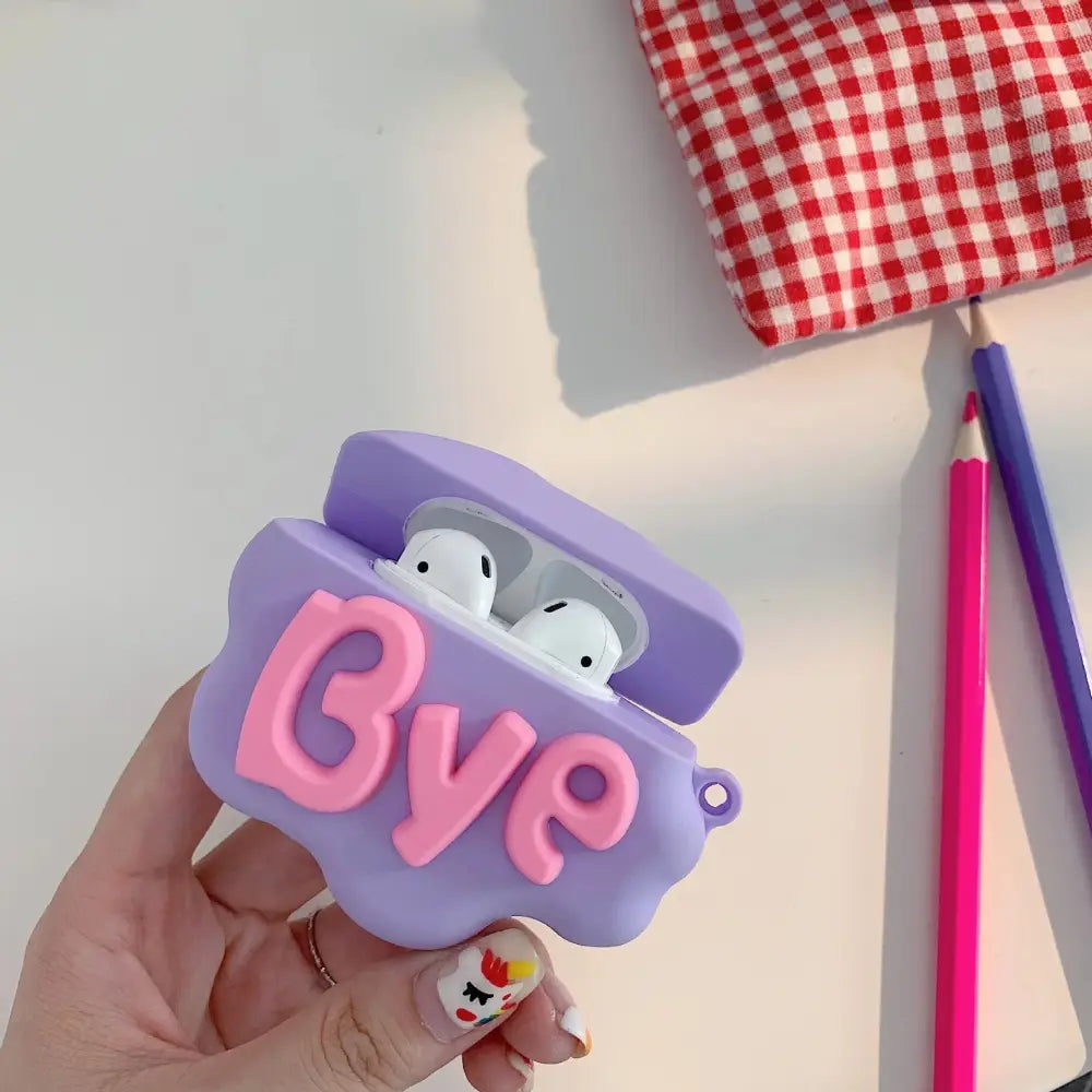 Purple silicone airpods 2 case with pink bye lettering in 3d hi bye speech bubble design shown from the back side
