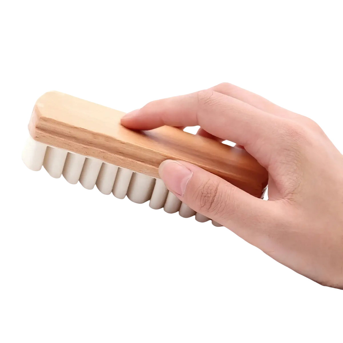 A hand holds a light brown wooden alcantara suede car interior cleaning brush with dense off-white bristles