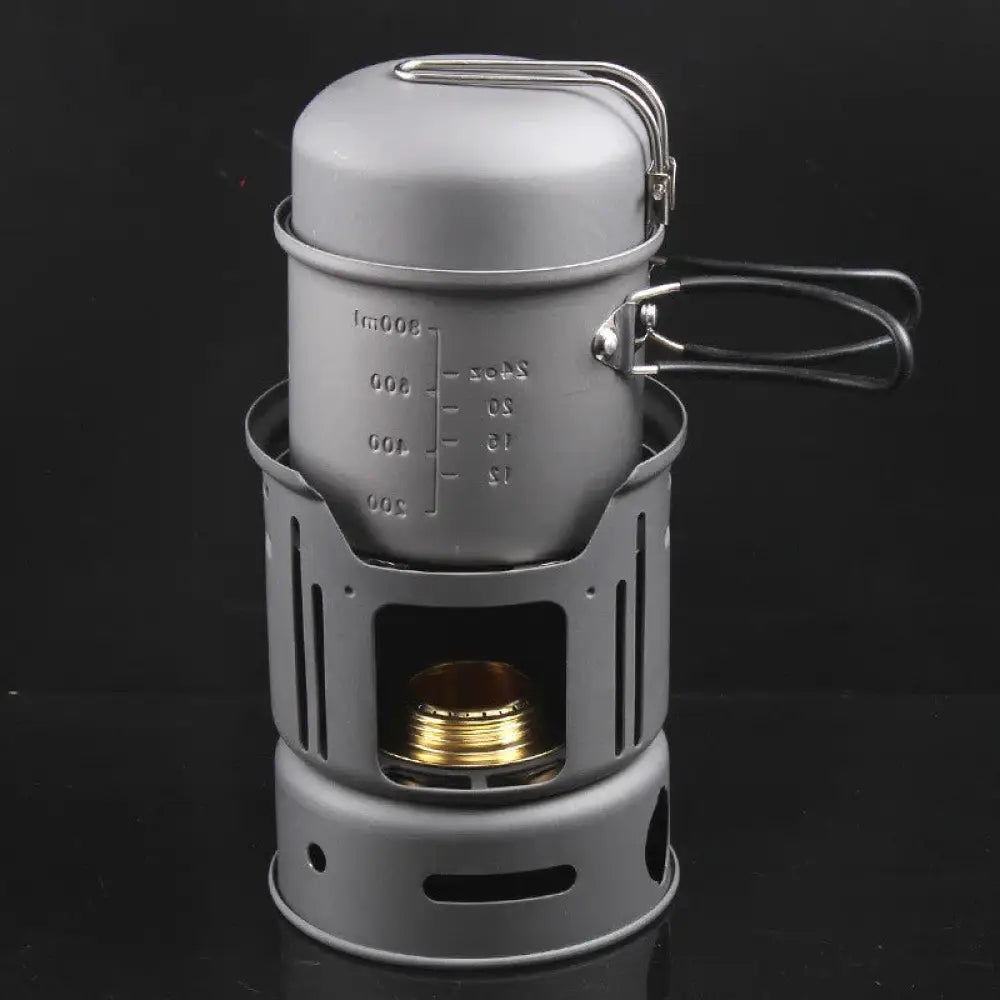 Gray aluminum portable camping stove with matching pot featuring measurement markings and wire handle for outdoor use