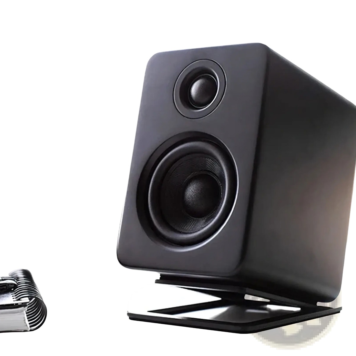 Black rectangular studio monitor speaker with matte finish and two circular drivers on aluminum desktop speaker stands with 16° tilt