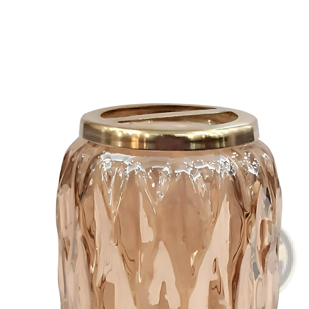 A rose gold textured glass candle holder with a polished brass lid featured in amber glass toothbrush holder with gold rim