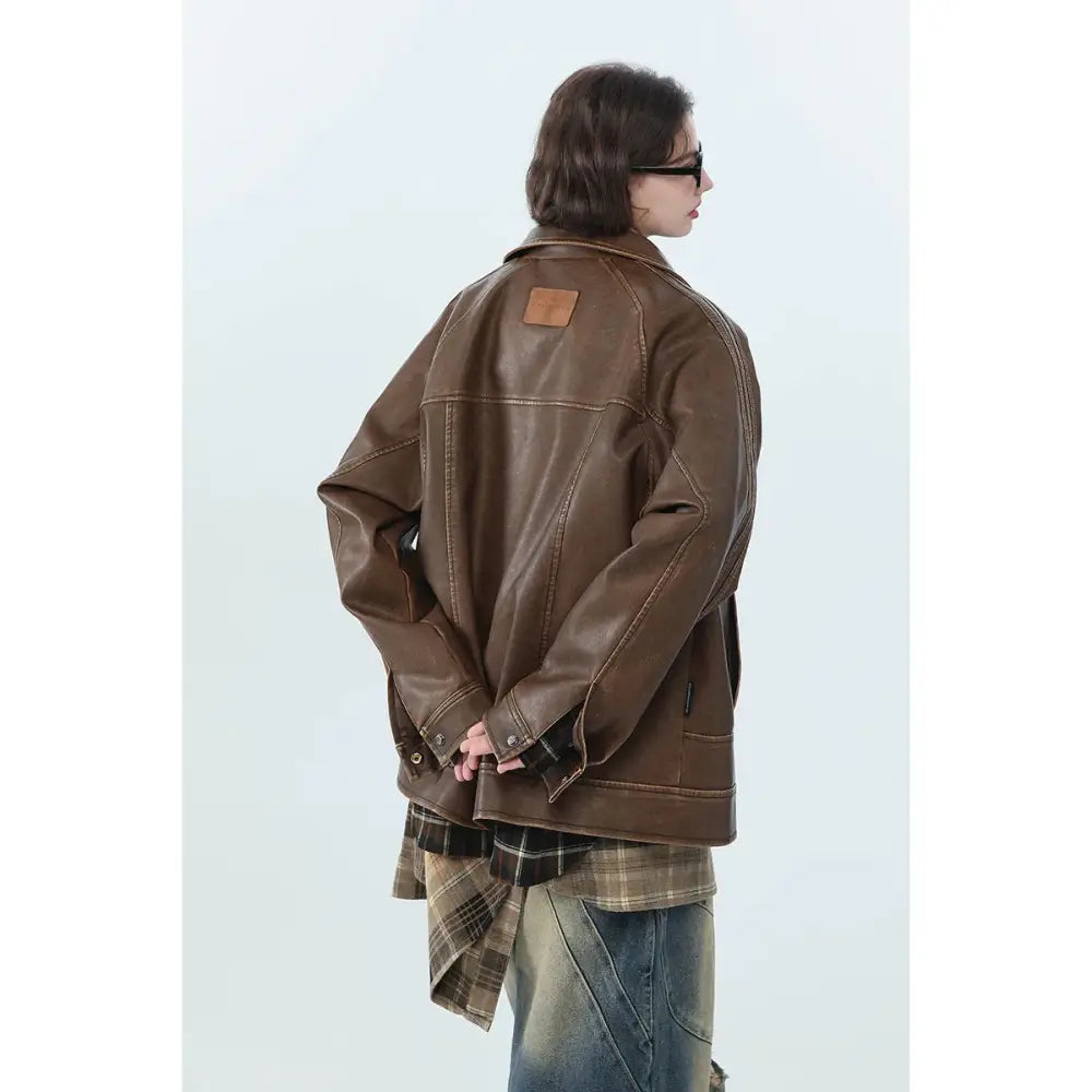Brown faux leather biker jacket with visible stitching and tan shoulder patch in retro distressed unisex style