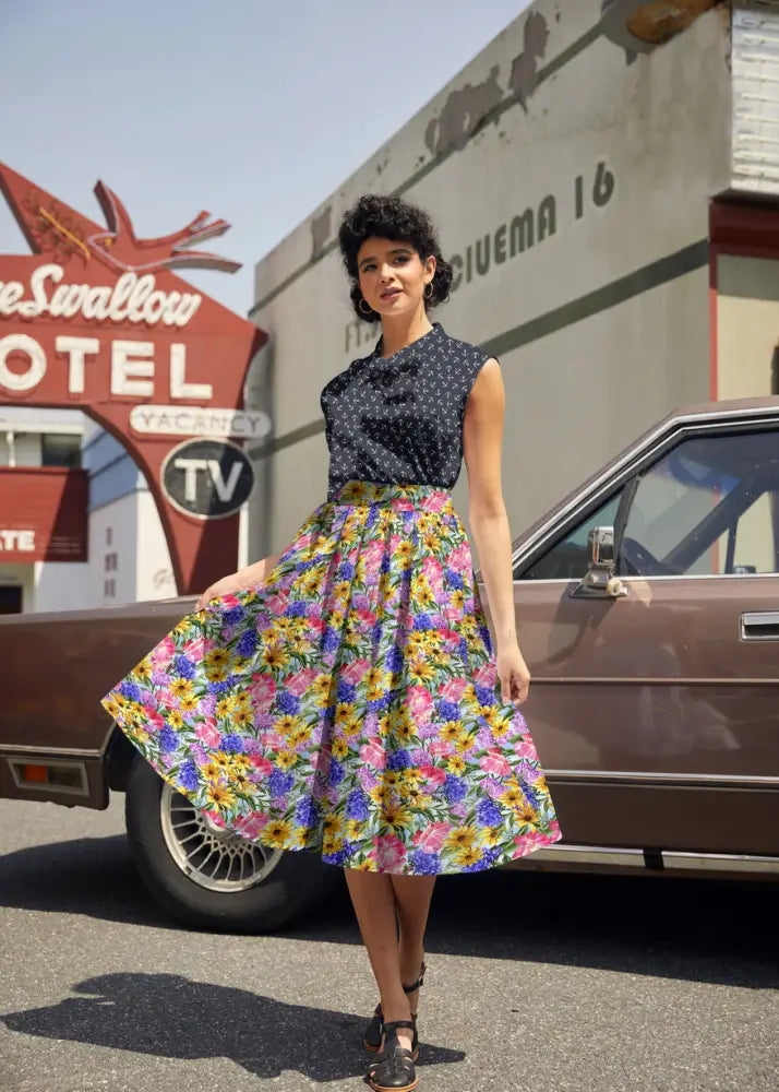 A woman wearing a vintage navy anchor print sleeveless bow top paired with a vibrant floral skirt with a full silhouette