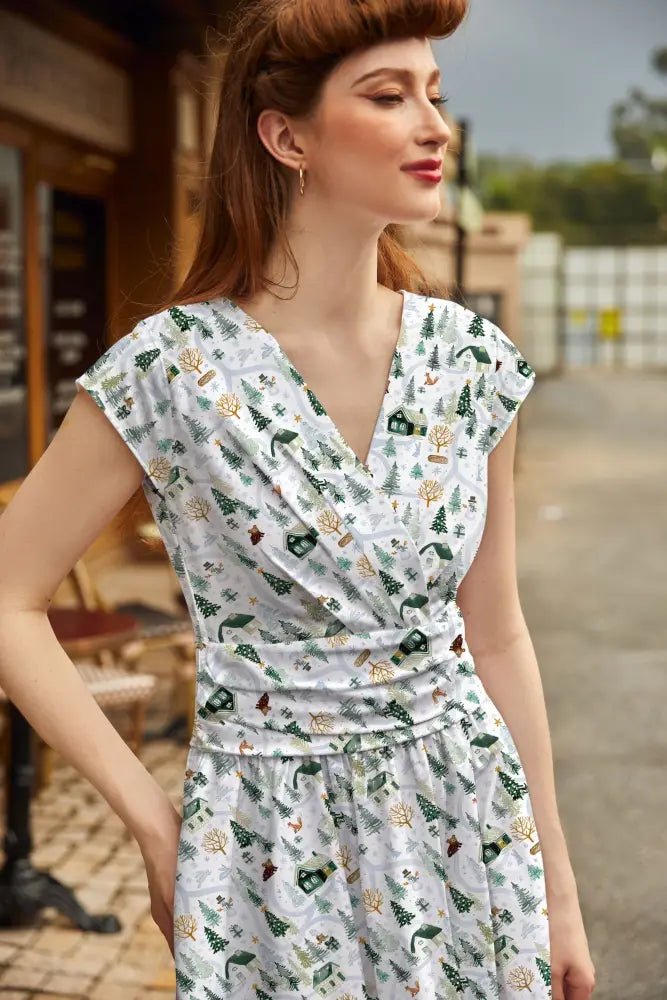 Animal Town Greta V-neck cotton holiday dress in white with green pine trees tiny houses and woodland creatures pattern