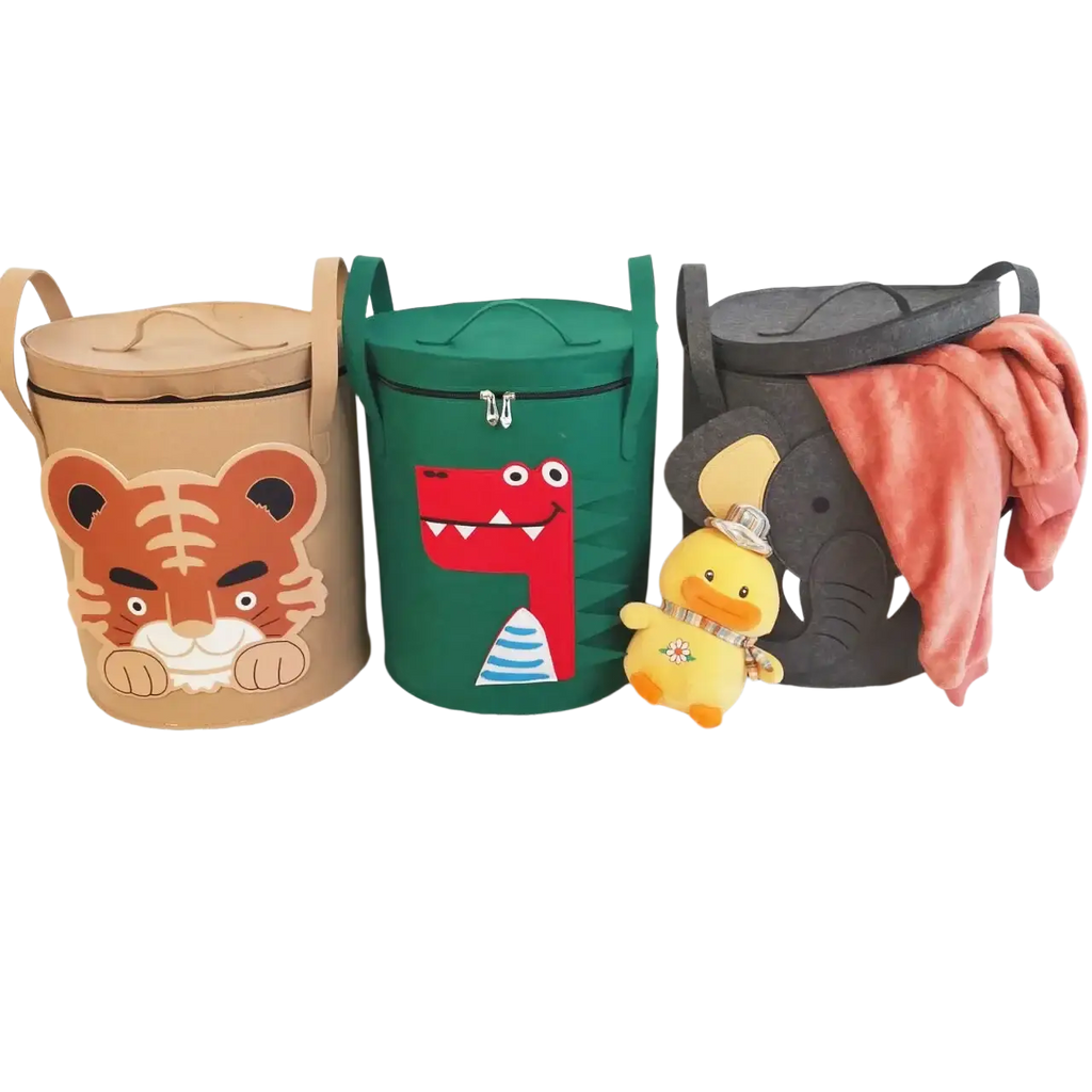Three cylindrical fabric animal toy storage baskets with lids and handles in tan tiger, green dinosaur, and black elephant designs