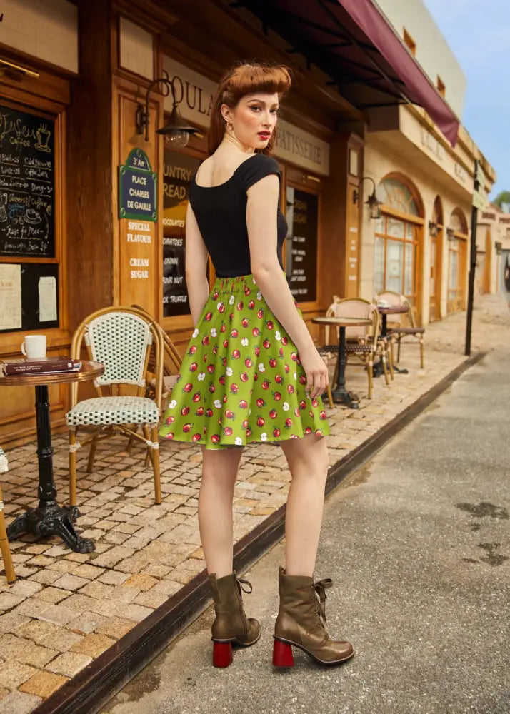 Apples print lime green pleated skater skirt featuring a green cherry print, flared hem, and fitted waistband
