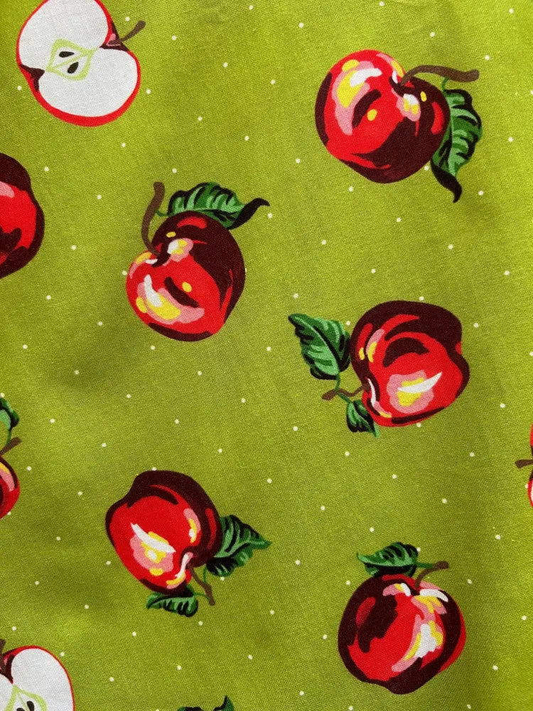 Vibrant lime green pleated skater skirt with playful red apples and white polka dot fabric pattern