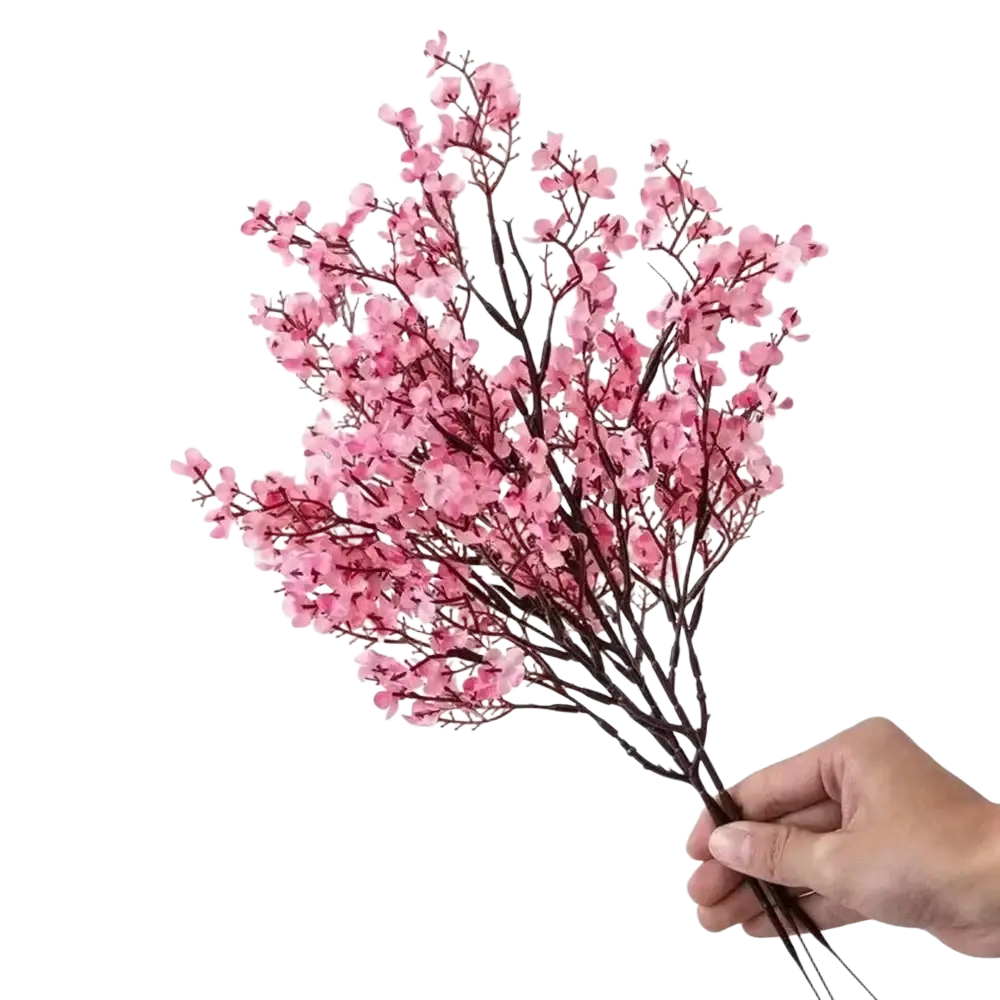 A delicate bouquet of artificial flowers cherry blossoms in pink with dark brown stems held gently in a hand
