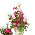 A vibrant artificial flowers wedding arch floral backdrop featuring pink and deep red roses in a cream vase