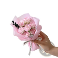 A delicate artificial rose flower bouquet with soft pink preserved roses wrapped in translucent paper for gifts