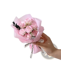 A delicate artificial rose flower bouquet with soft pink preserved roses wrapped in translucent paper for gifts