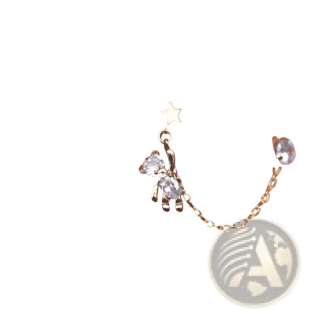Gold-toned asymmetrical ear cuffs featuring a star charm, crystal bear tassel, and connecting delicate chain with rhinestones