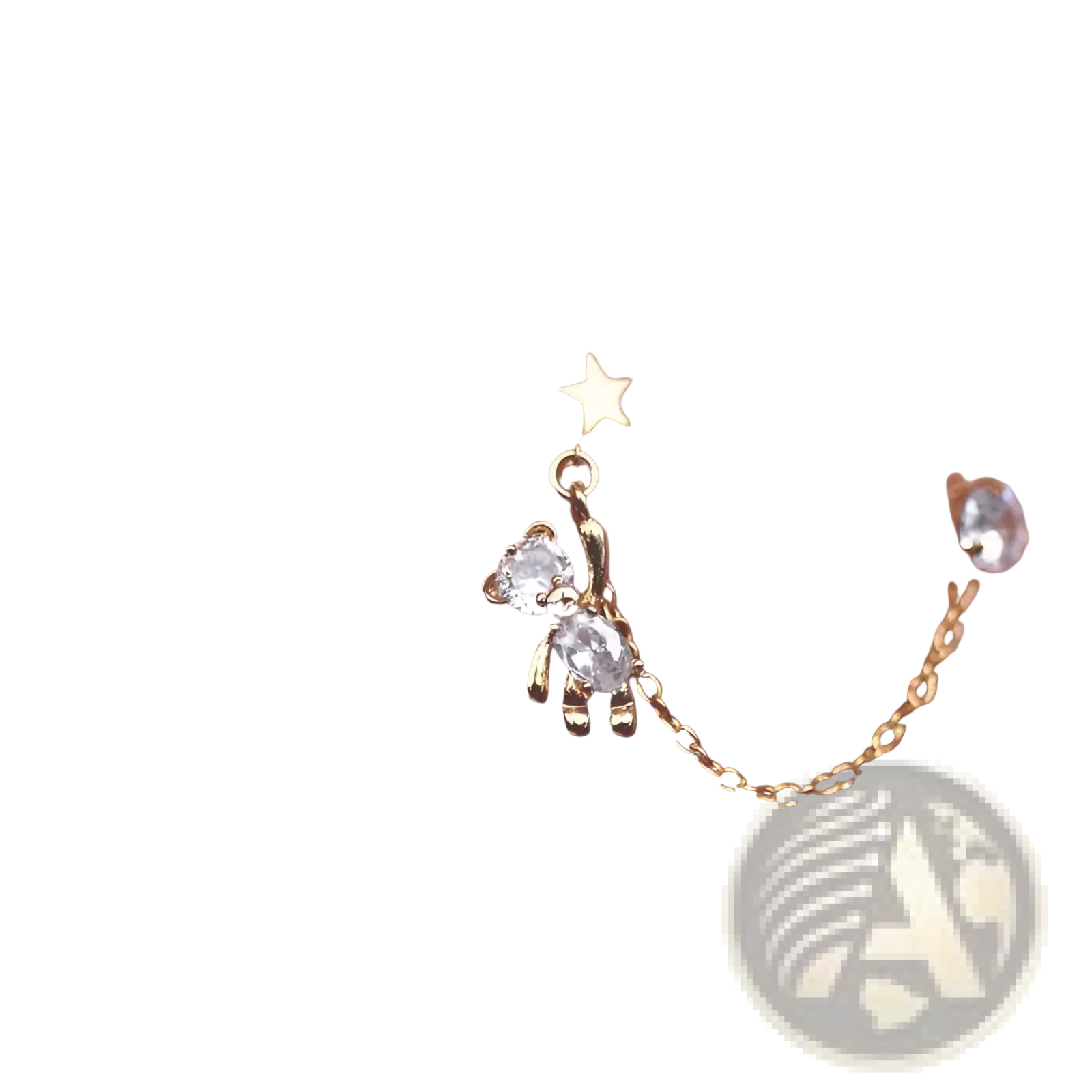Gold-toned asymmetrical ear cuffs featuring a star charm, crystal bear tassel, and connecting delicate chain with rhinestones