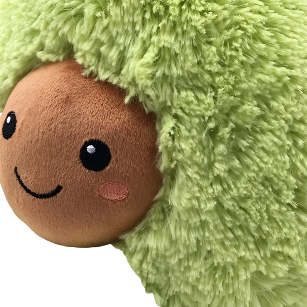 A soft plush avocado stuffed toy with a brown smiling face and black eyes serving as a cartoon pillow
