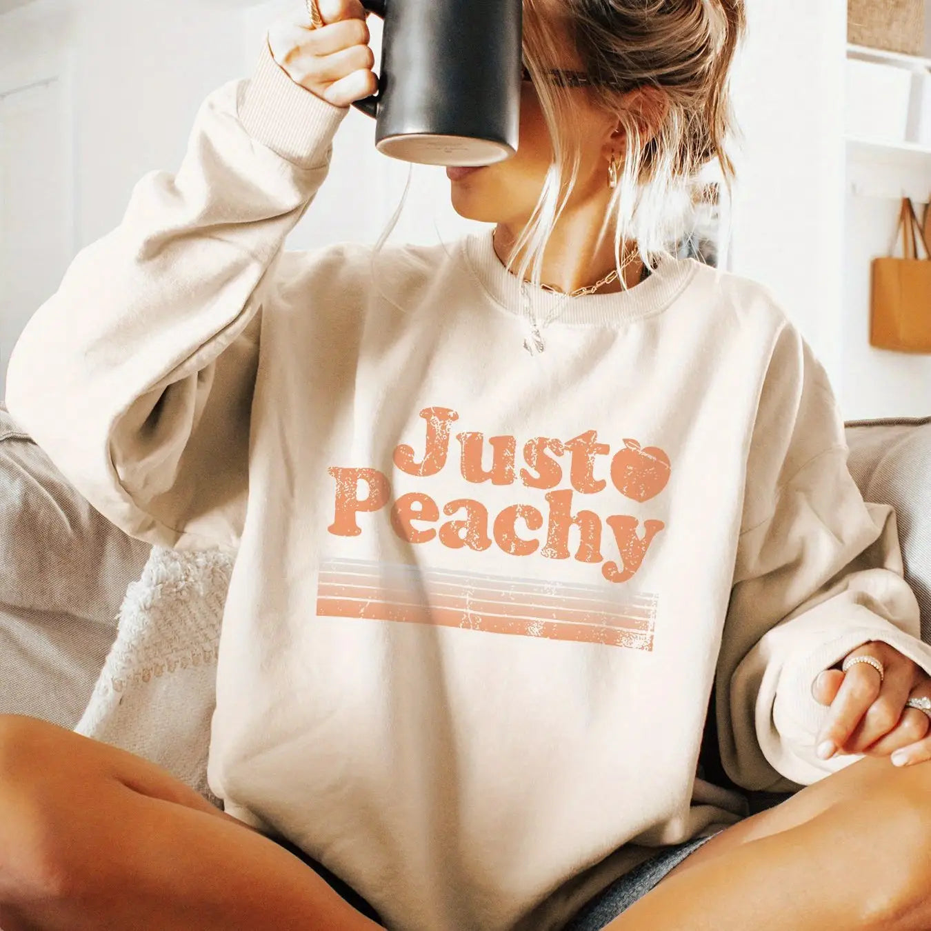 Sudadera extragrande de color crema con un gráfico desgastado «just peachy» en color naranja y un icono de durazno.