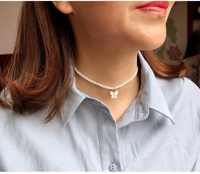 A delicate pearl choker necklace featuring a small white butterfly pendant from the elegant pearl butterfly charm choker necklace collection.