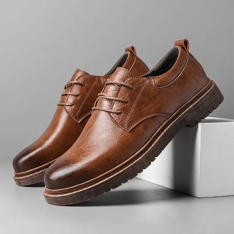 Black leather lace-up oxford shoe with brown rubber sole and stitched detailing for men’s business and casual wear.