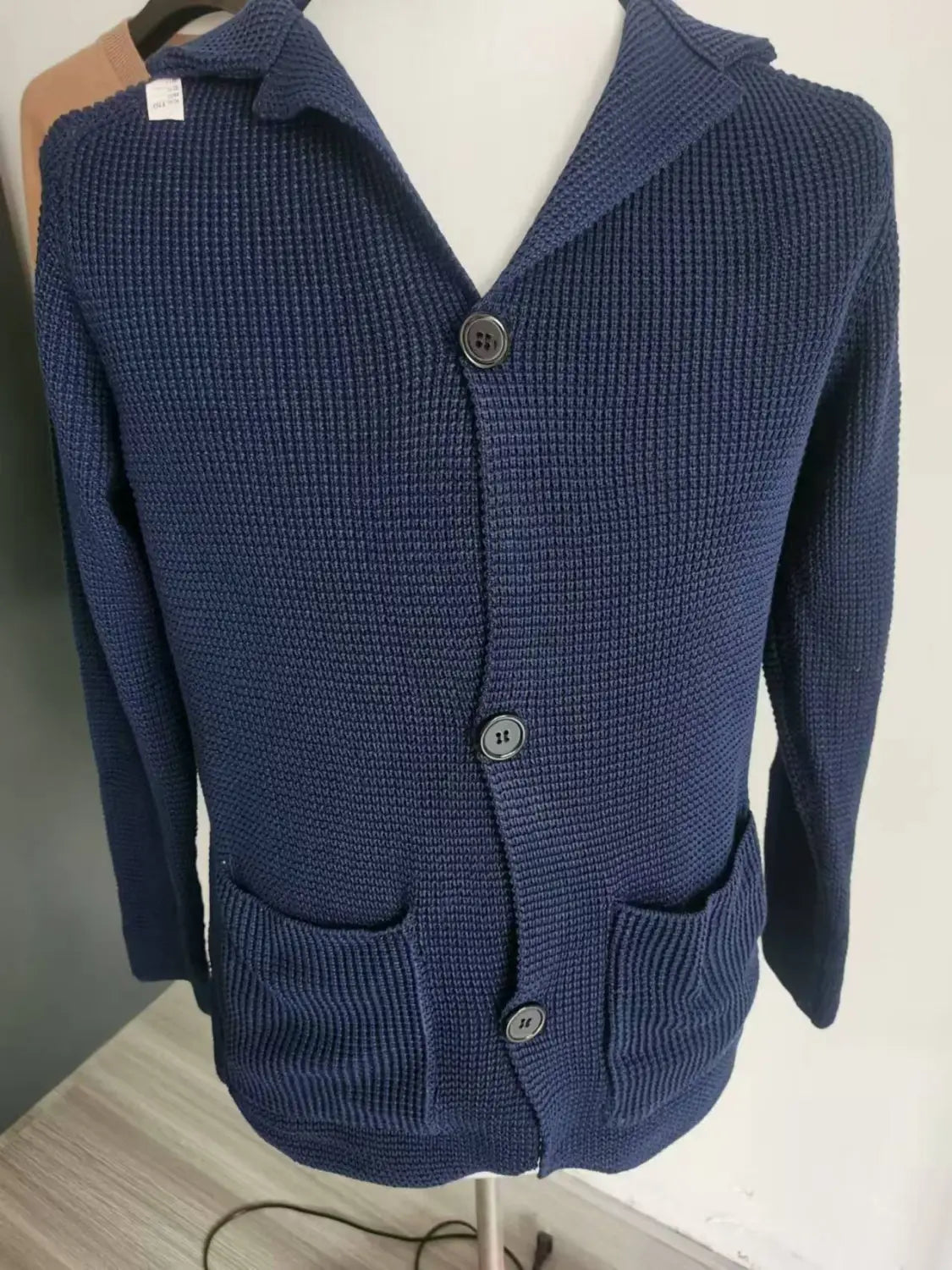 Cardigan en maille côtelée bleu marine pour homme, avec col montant, trois boutons gris foncé et deux poches avant.