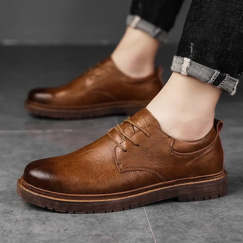 Black leather lace-up oxford shoe with brown rubber sole and stitched detailing for men’s business and casual wear.