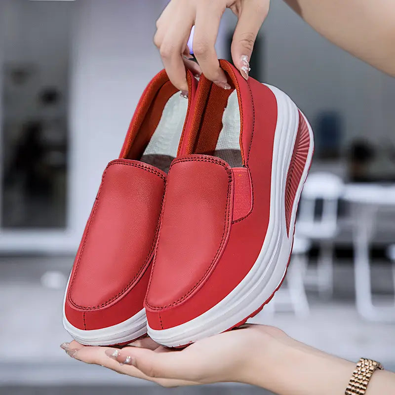 Chaussures en cuir à talon compensé en forme de coin rouge, modèle slip-on, rouge, avec une semelle intérieure blanche rembourrée et des bandes latérales discrètes.