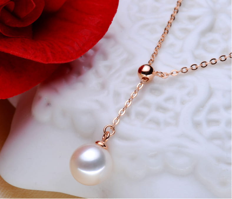 An adjustable pearl lariat necklace in rose gold featuring a delicate chain and a single lustrous white pearl pendant.