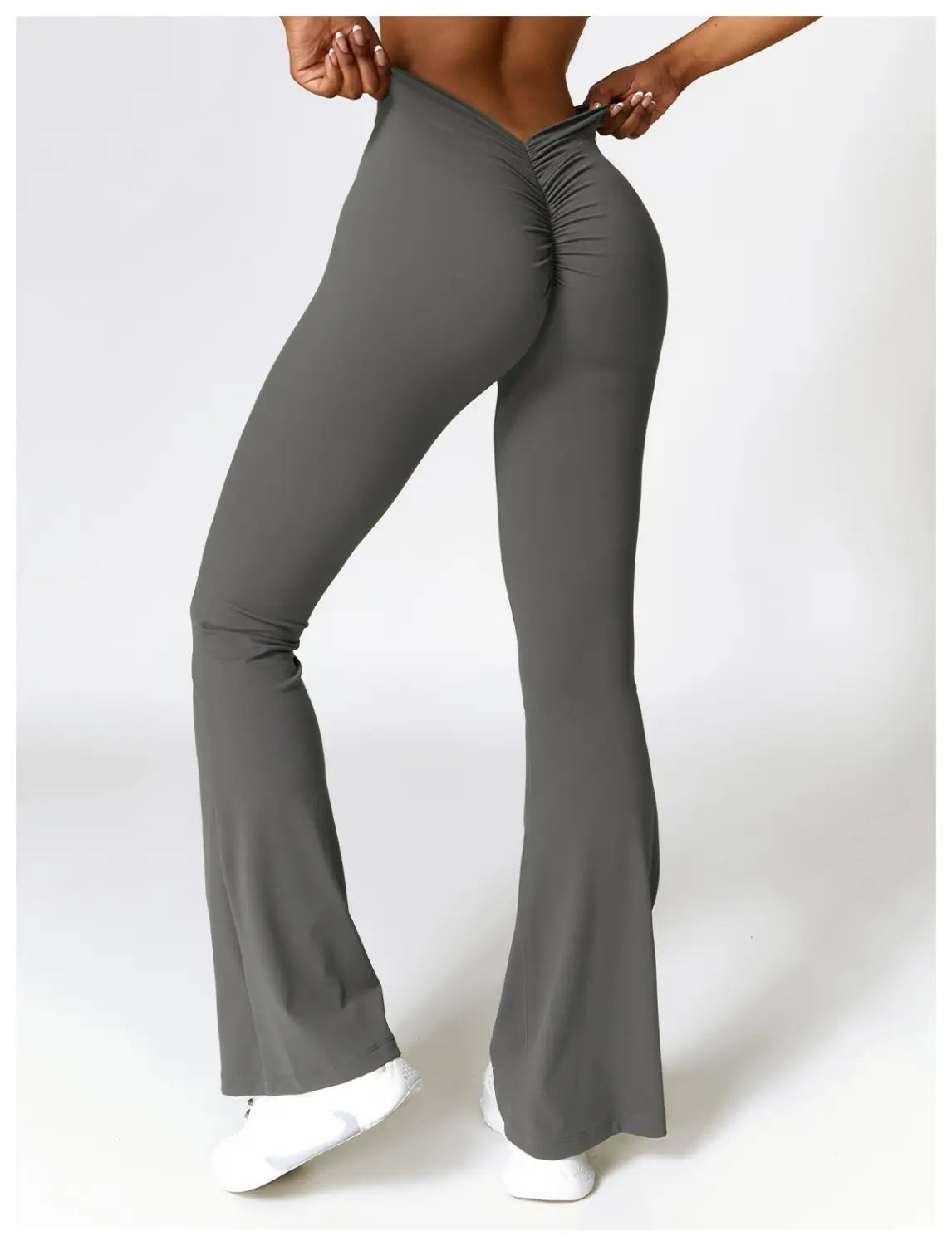 high-waist flared yoga pants in gray stretchy fabric with a ruched back design shown from the back side.