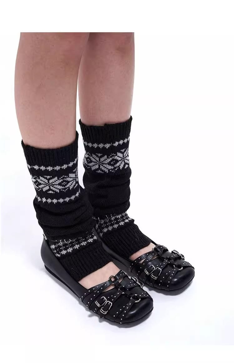 polainas de punto negras con copos de nieve blancos y patrones geométricos, combinadas con zapatos tipo salón retro de cuero con correas de hebilla con tachuelas.