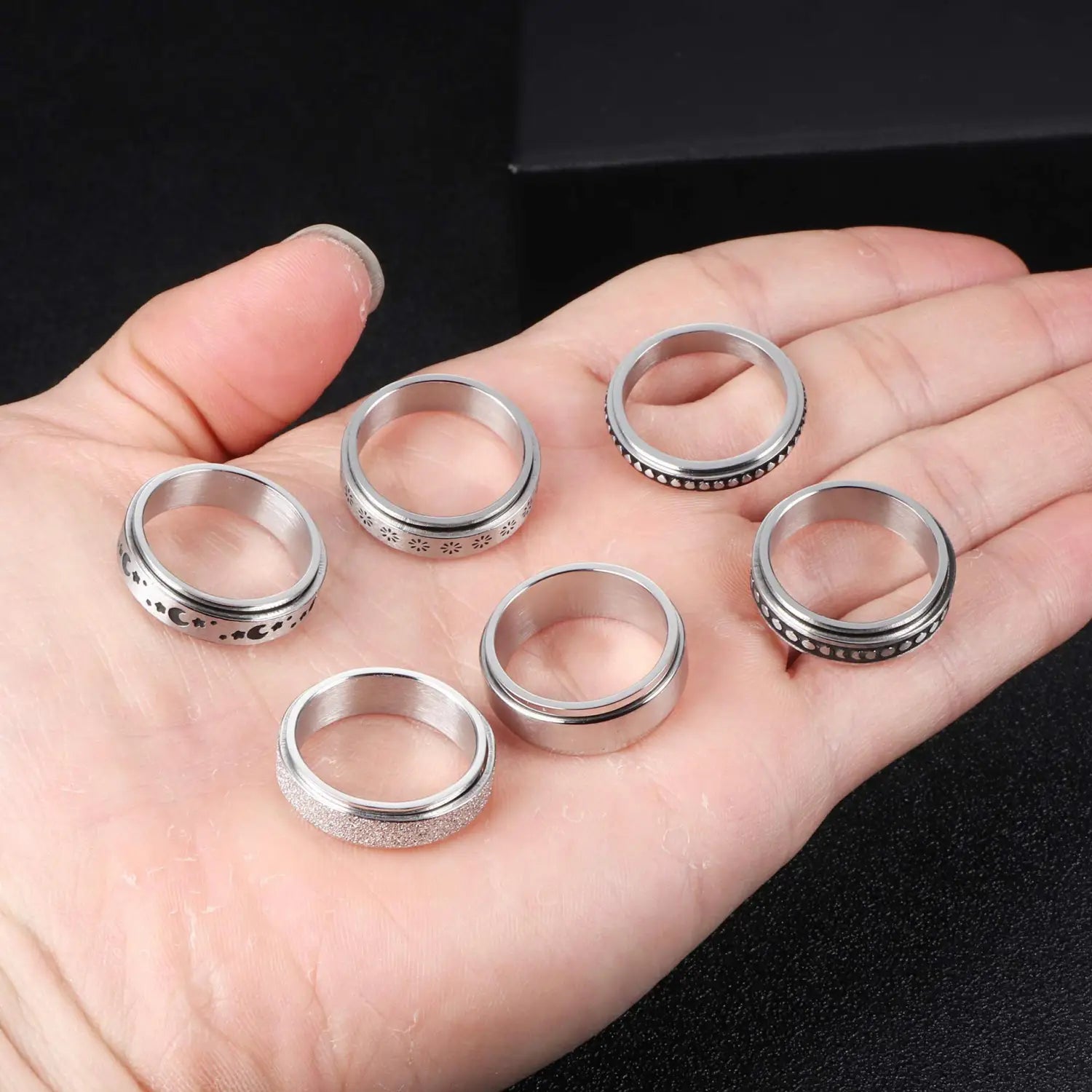 Set of six silver-toned stainless steel spinner rings with intricate engraved patterns and textured surfaces designed for anxiety relief in the celestial stainless steel anxiety spinner ring set.