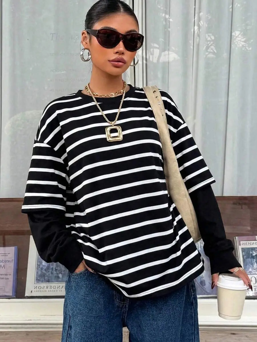 Top oversize de manga larga con rayas horizontales negro y blanco y apariencia en capas, que se presenta en el producto de sudadera oversize tipo conjunto falso de dos piezas con rayas.