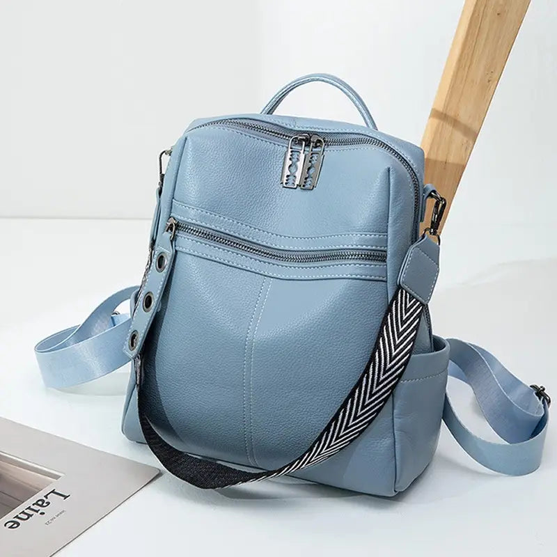 Light blue urban faux leather backpack with a contrasting black and white herringbone patterned strap, silver-toned zippers, and a decorative metal clasp.