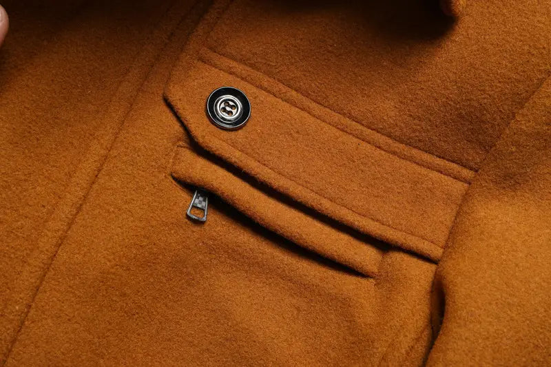 A dark metallic button with a circular design is featured on the chest pocket of an orange wool men wool winter overcoat quilted jacket.