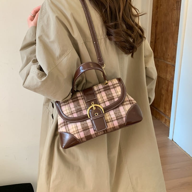 Bolso bandolera vintage de cuadros que presenta tela de cuadros marrón y beige con ribete de cuero, un cierre con broche de hebilla en tono dorado y una correa para el hombro a juego.