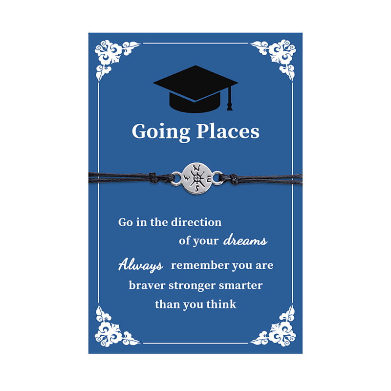 Silver compass charm graduation adventure cord bracelet with black cord displayed on a blue card featuring a graduation cap and motivational text.