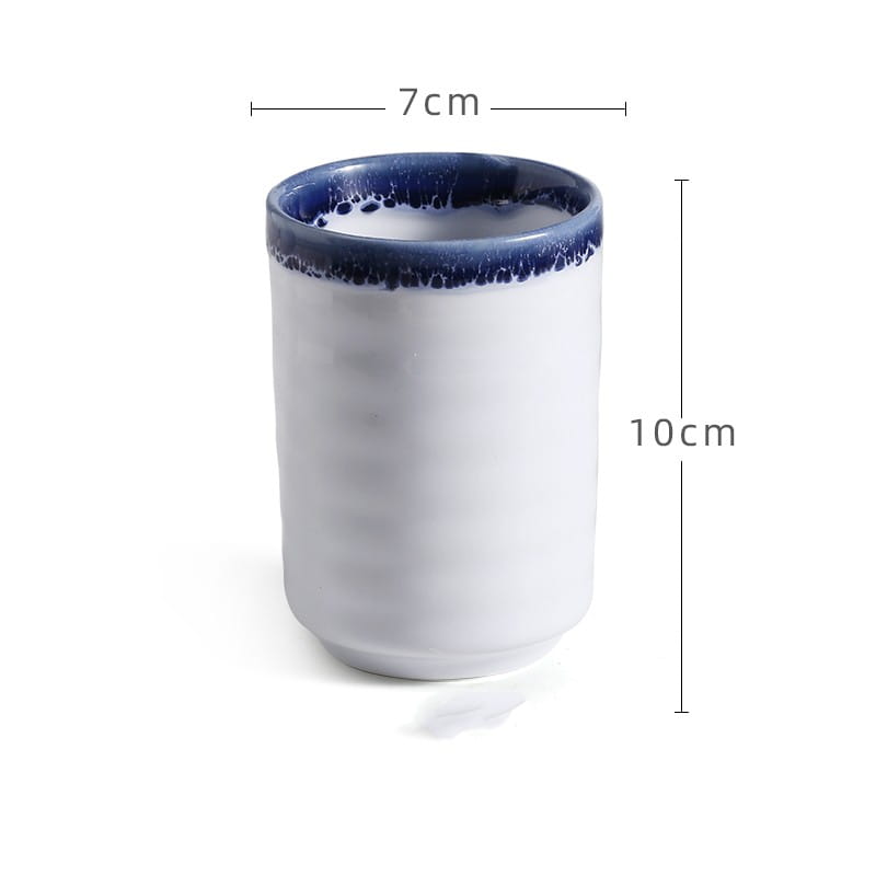 A white ceramic Japanese ceramic mug with a textured surface and blue speckled rim designed as a retro hand-painted tea cup with a 250ml capacity.