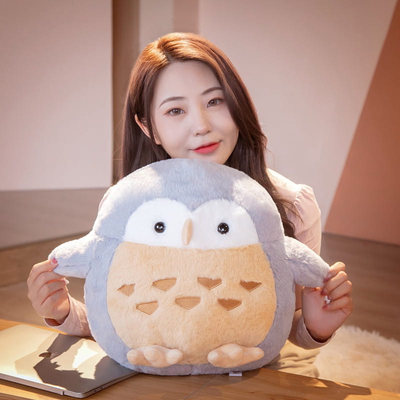 Soft gray and beige plush owl cushion with embroidered heart details featured as a round soft doll toy stuffed animal.