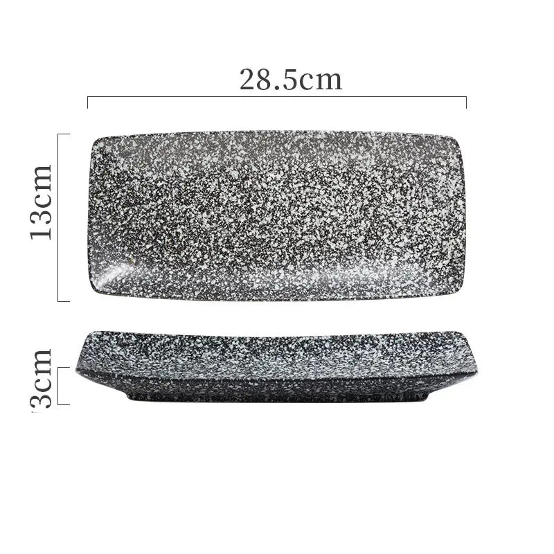 A rectangular ceramic sushi plate with a speckled black and white surface measuring 28.5cm by 13cm designed for serving food.