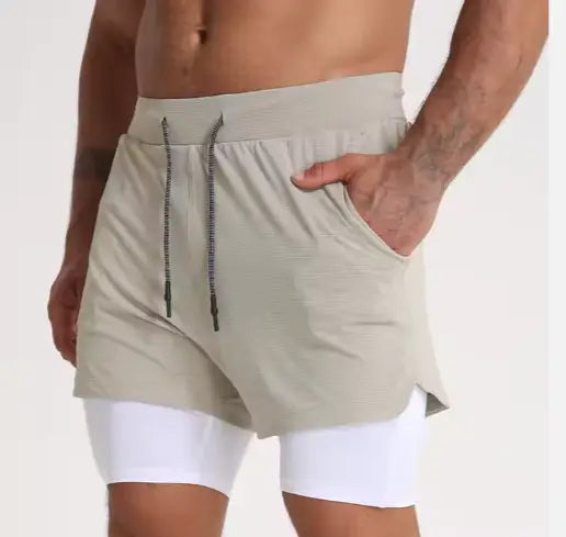 Men’s beige 2-in-1 breathable quick dry athletic training shorts with drawstring waistband and side pockets worn over white compression leggings.