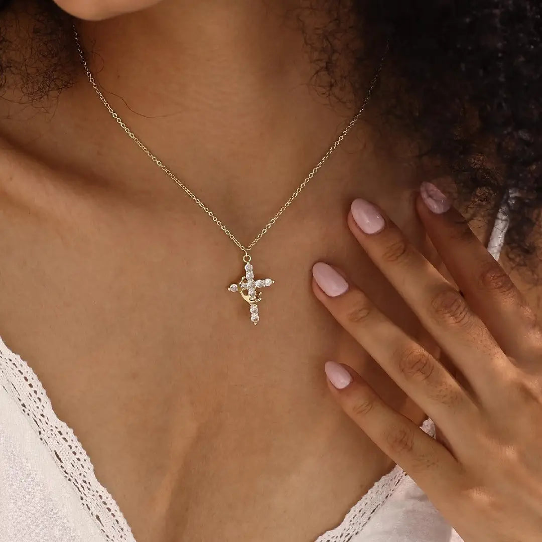 A delicate gold chain necklace featuring a cross pendant adorned with sparkling clear stones from the sparkling layered crown and cross pendant necklace collection.