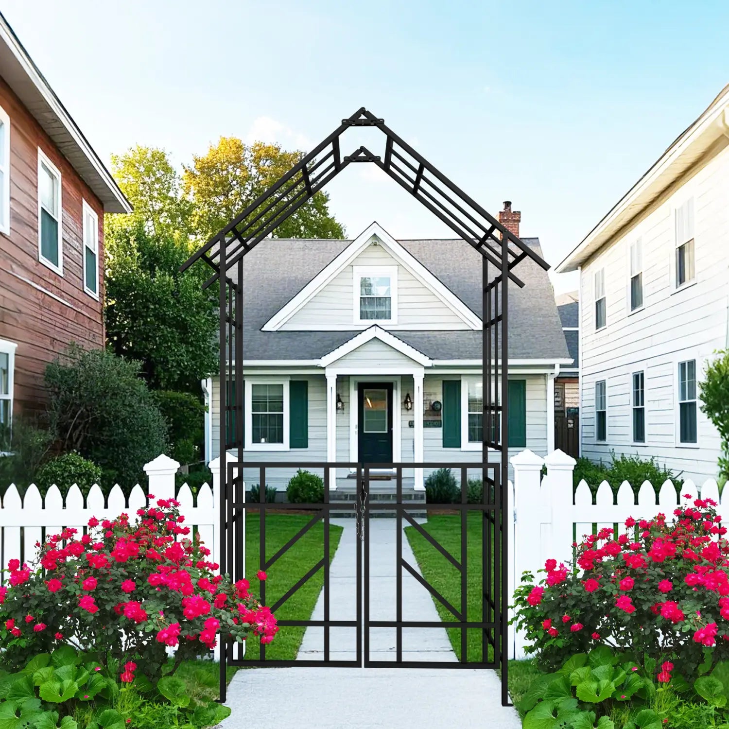 Black wrought iron metal garden arch with gate featuring a triangular top and vertical slats flanked by vibrant pink rose bushes