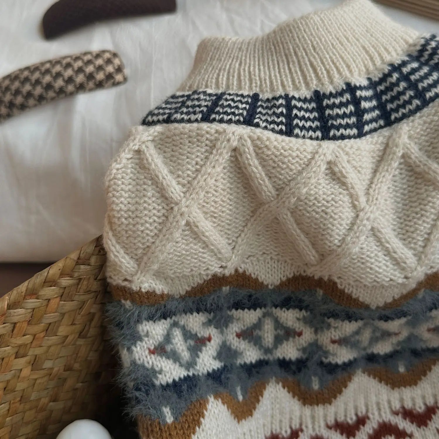 Pull pour chien tricoté couleur crème avec encolure côtelée, centre en point torsadé à motifs de losanges complexes, et bandes géométriques décoratives en bleu marine, gris, brun et rouge vintage, vêtement pour animal de compagnie.