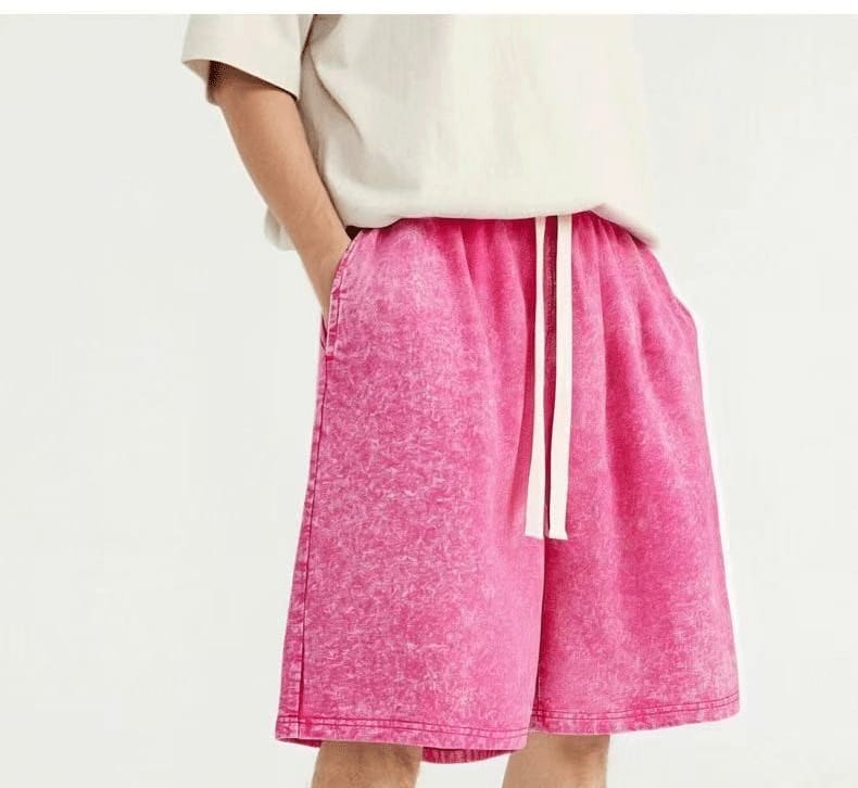 Bright pink slightly faded denim mens distressed cotton shorts with a white drawstring waistband suitable for vintage summer apparel.